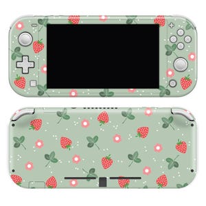 May include: A green and white Nintendo Switch Lite console skin with a pattern of red strawberries and green leaves.