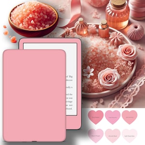 May include: A pink e-reader with a white screen and a pink case. The e-reader is sitting on a table with a bowl of pink Himalayan salt, a pink rose, and other pink decorations.