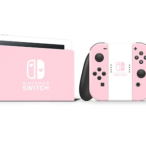 May include: A pink Nintendo Switch console and controllers. The console is in a docking station. The controllers are pink and white with black accents. The Nintendo Switch logo is visible on the console and controllers.