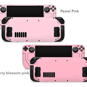 May include: Two pink handheld gaming consoles with black buttons and a screen. The top console is labelled "Pastel Pink" and the bottom console is labelled "Cherry blossom pink".
