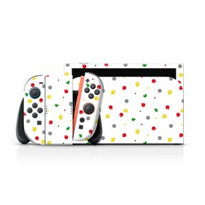 May include: A white Nintendo Switch console and Joy-Con controllers with a colorful pattern of red, green, yellow, and gray shapes. The controllers are black and white with black buttons. The console has a black screen.