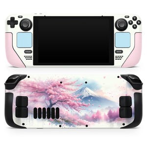 May include: A pink and white handheld gaming console with a colorful image of a cherry blossom tree and a mountain on the back. The console has a black screen and black buttons.