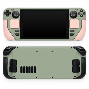 May include: A handheld gaming console featuring a sage green body with pale pink accents on the side grips and trackpads. The front displays a black screen, black buttons, and joysticks. The back is sage green with black triggers and vents.