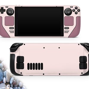 May include: A handheld gaming console in a light pink and mauve color scheme. The front features a black screen, control buttons, and a directional pad. The back has black grips and vents. The console is shown from the front and back.