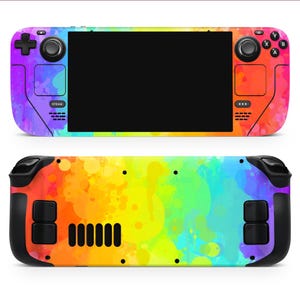 May include: A handheld gaming console with a vibrant rainbow watercolour design. The front features a black screen, buttons, and a joystick. The back has black grips and a colourful splash pattern. The console is designed for gaming.