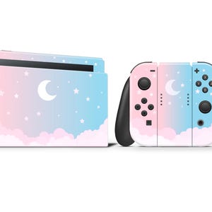 May include: A Nintendo Switch console and controllers with a pastel sky design. The console and controllers feature a pink and blue gradient with white clouds, stars, and a crescent moon. The controllers have black grips.