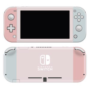Könnte beinhalten: Eine rosa und hellblaue Nintendo Switch Konsole mit einem weißen Herzdesign auf der Rückseite. Die Konsole hat einen weißen Bildschirm und ein weißes Nintendo Switch Logo.