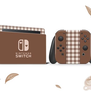 Può includere: Una console e un controller Nintendo Switch a scacchi marroni e bianchi con un logo a forma di cuore rosa e il testo "NINTENDO SWITCH".