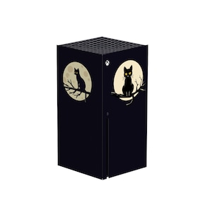 May include: Black Xbox Series X console skin with a Halloween theme. The design features a black cat sitting on a branch in front of a full moon.