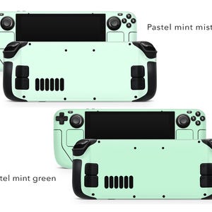 May include: Two Nintendo Switch Lite consoles with pastel green and pastel mint mist coloured shells. The consoles are shown side-by-side. The top console has a black screen and the bottom console has a black screen.