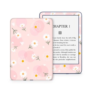 May include: A pink and white floral pattern Kindle Paperwhite e-reader case with a white daisy pattern. The case has a navy blue trim. The e-reader screen displays the text "CHAPTER 1" and a short excerpt from a book.