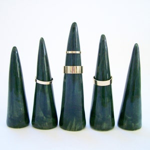 May include: Five green ceramic ring cones with gold rings on each cone.