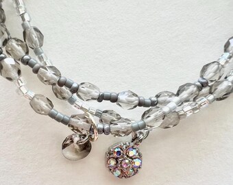 Conjunto de pulsera de cristal gris y cuentas pequeñas con dijes.