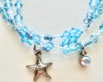 Conjunto de pulsera de cristal azul claro y cuentas pequeñas con dijes.