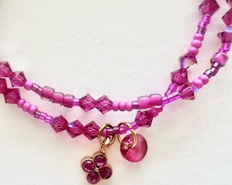 Conjunto de pulsera de cristal fucsia y cuentas pequeñas con dijes.