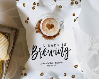 May include: White snack bag with coffee bean illustrations and the text "A Baby Is Brewing." The bag features a coffee cup design with a heart-shaped foam design. The text "Allison's Baby Shower 06.01.30" is also printed on the bag.