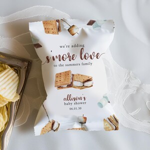 May include: White favor bag with a brown and white s'more design. The bag has the text "we're adding s'more love to the summers family" and "allison's baby shower 06.01.30".