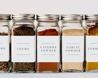 May include: Five glass spice jars with white labels and black text. The labels read "Oregano", "Thyme", "Cayenne Powder", "Garlic Powder", and "Turmeric".