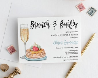 May include: A white invitation card with blue and black text for a bridal shower brunch. The text reads "Brunch & Bubbly" and includes the bride's name, date, time, location, and RSVP information. The card is decorated with a watercolour illustration of a glass of champagne and a stack of pancakes with strawberries and whipped cream.
