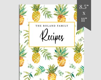 May include: A white recipe book cover with a yellow border and the text "THE ROLAND FAMILY Recipes" in black. The background features a repeating pattern of watercolor pineapples and green leaves.