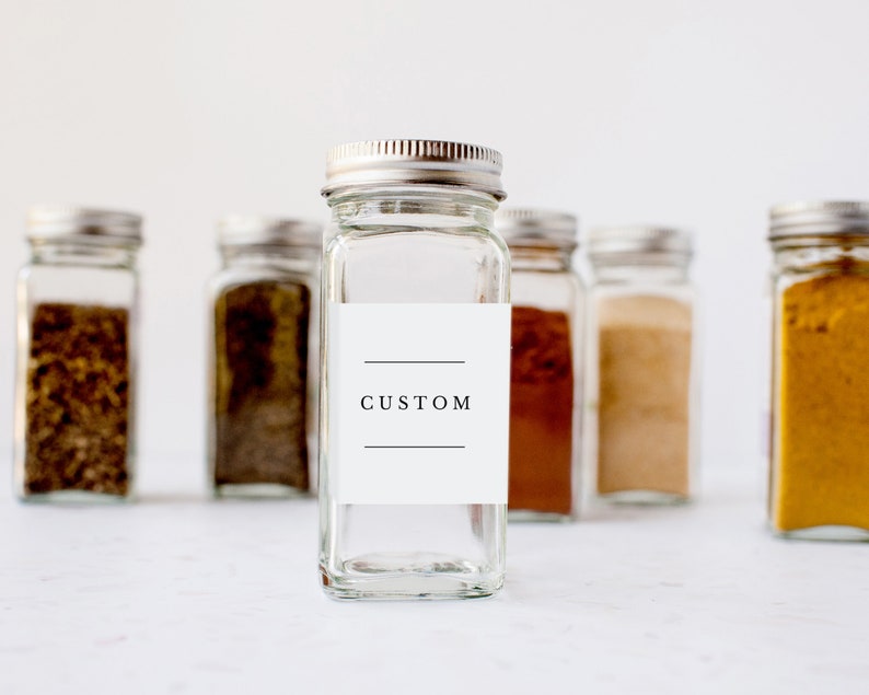 May include: A set of six glass spice jars with silver lids. The centre jar has a white label with the word "CUSTOM" printed on it.
