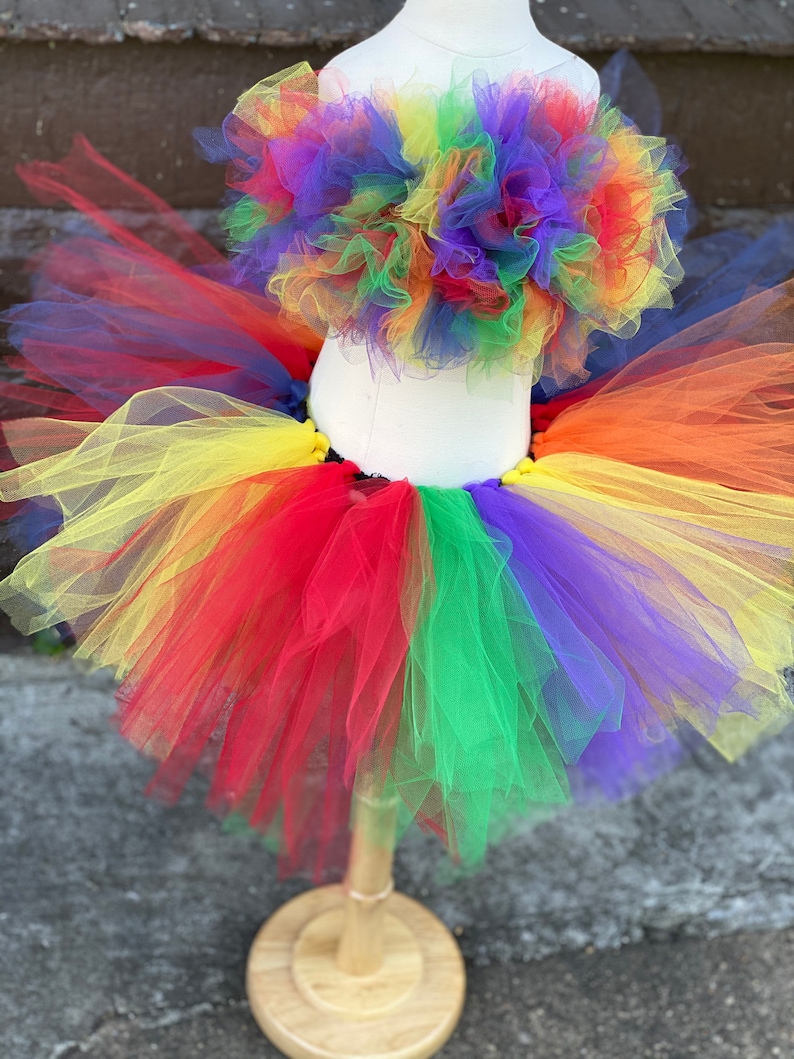 Op de afbeelding: Regenboog tule rok en bijpassend topje. De rok is gelaagd met tule in rood, oranje, geel, groen, blauw en paars. Het topje is een strapless bandeau.