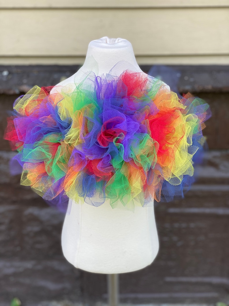 Op de afbeelding: Een regenboog tule top met een gerimpeld ontwerp. De top is gemaakt van meerdere lagen tule in verschillende kleuren, waaronder rood, oranje, geel, groen, blauw, indigo en violet.