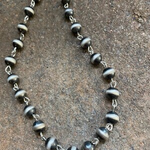 May include: A black and white beaded necklace with silver chain links. The beads are round and have a striped pattern.