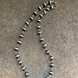 May include: A black and white beaded necklace with a silver clasp. The beads are round and have a striped pattern.