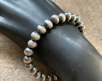 May include: A silver bracelet with round beads. The beads have a brushed finish and are slightly uneven in size.