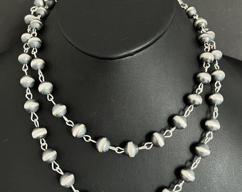 May include: A silver necklace with round, gray and white beads. The necklace is layered and has a chain link design.