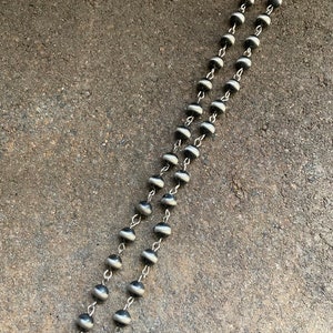 May include: A black and white beaded necklace with a silver clasp. The beads are round and have a striped pattern.