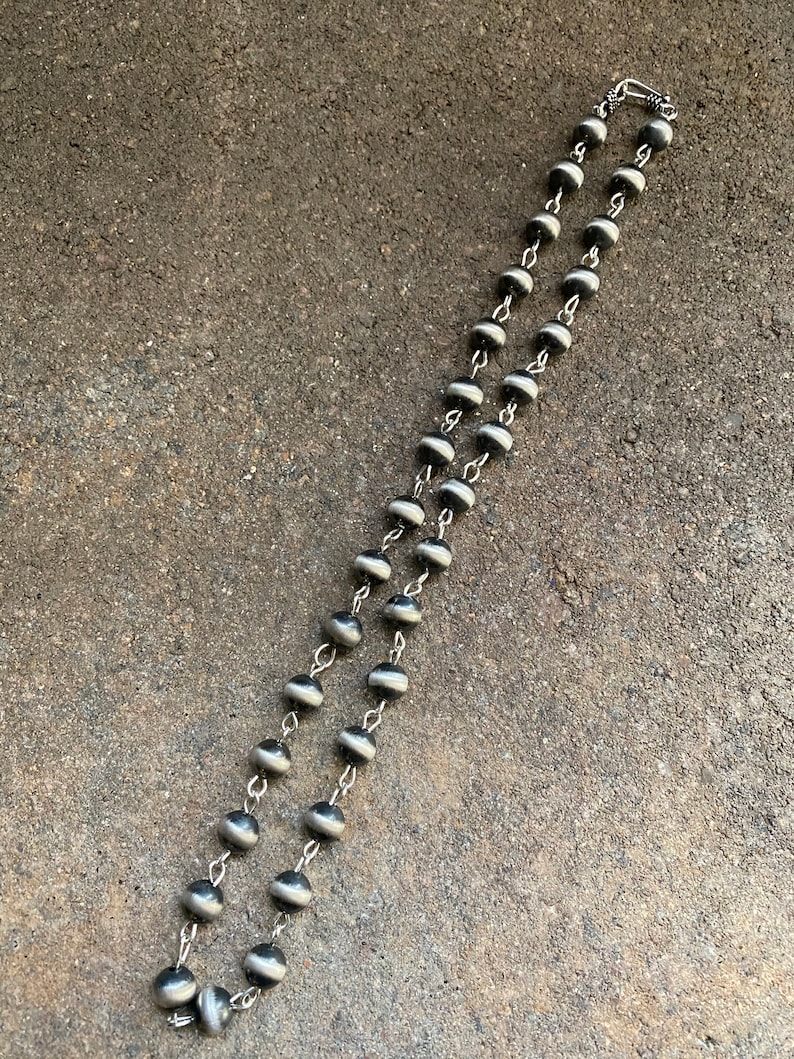 May include: A black and white beaded necklace with a silver clasp. The beads are round and have a striped pattern.