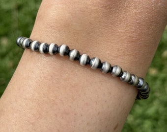 May include: A silver bracelet with round beads. The beads are a mix of black and silver.