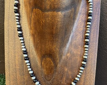 Könnte beinhalten: Eine silberne und schwarze Perlenkette mit schlichtem Design. Die Kette besteht aus runden Perlen und ist etwa 45 cm lang.