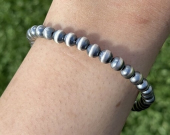 May include: A silver bracelet with white and black striped beads.