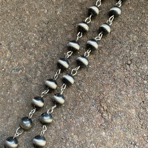May include: A silver chain with black and white beads. The beads have a smooth, shiny finish.