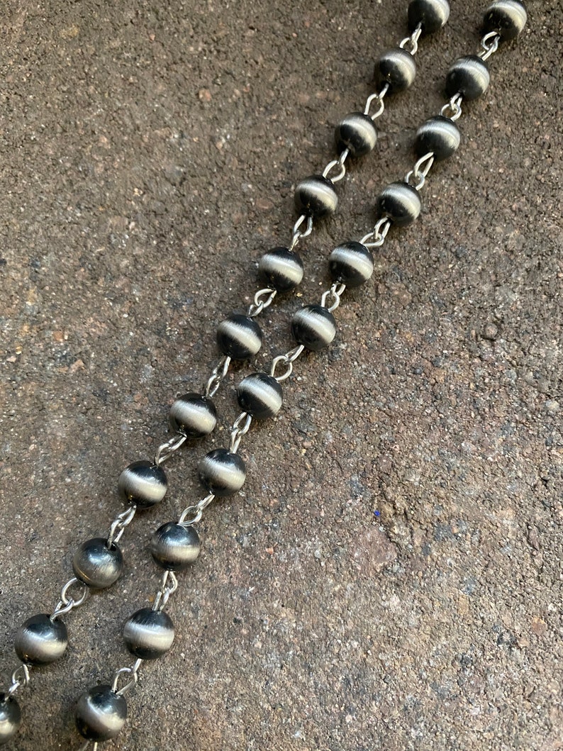 May include: A silver chain with black and white beads. The beads have a smooth, shiny finish.