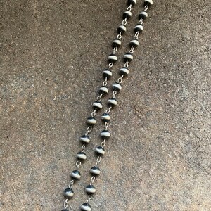 May include: A silver chain necklace with black and white beads. The beads are round and have a smooth, polished finish.