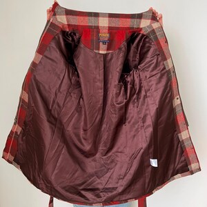 Op de afbeelding: Open geruite jas in rood, bruin en beige, met een donkerbruine satijnen voering. De jas heeft een knoopsluiting en een strikceintuur. Het Pendleton-label is zichtbaar.