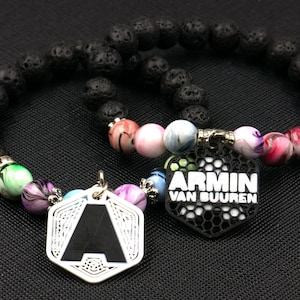 May include: Two black lava rock bracelets with colorful glass beads and metal charms. One charm features the letter "A" and the other says "Armin van Buuren".