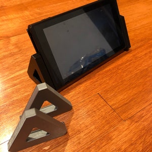 May include: A black Nintendo Switch console stand with a gray plastic stand for the Joy-Cons.