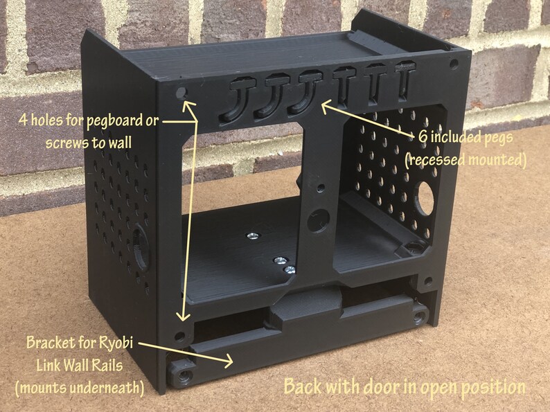 May include: Black plastic wall mount with a door that opens. It has six pegs and four holes for mounting to a wall. The mount is designed to hold Ryobi Link Wall Rails.