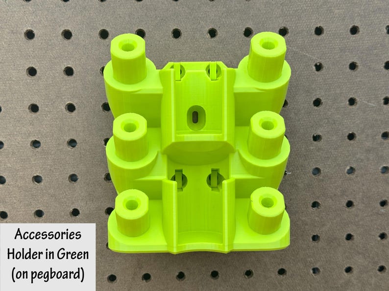 May include: A bright green accessory holder, designed for use with a pegboard. The holder features a rectangular base with several cylindrical posts and a central compartment. The text "Accessories Holder in Green (on pegboard)" is visible.