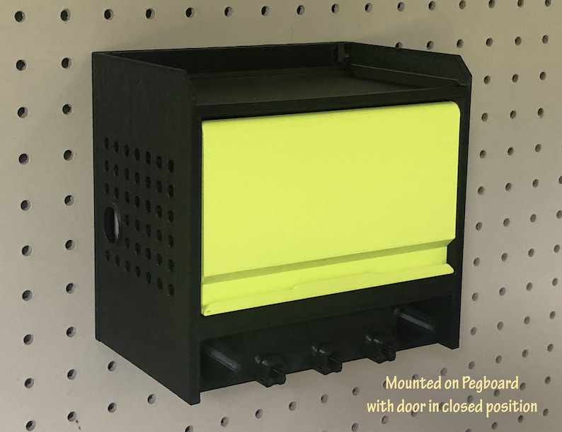 May include: Black pegboard storage unit with a bright yellow door. The door is closed and the unit is mounted on a pegboard wall.