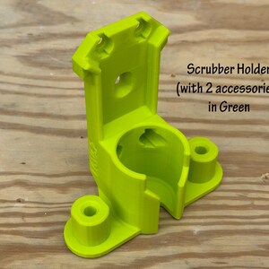 May include: A bright green scrubber holder with two accessory holders. The holder is made of plastic and has a cylindrical opening for the scrubber. The text "Scrubber Holder (with 2 accessories) in Green" is visible.