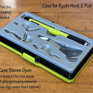 Può includere: Scatola aperta per un set di ganci e pinzette Ryobi. La scatola è verde e nera con un interno grigio. Gli strumenti sono visibili all'interno della scatola.