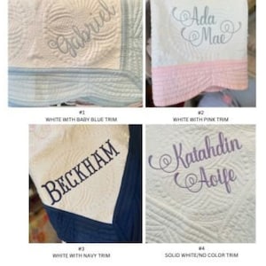 May include: Four white baby blankets with different coloured trim. The blankets are embroidered with names, including "Gabriel", "Ada Mae", "Beckham", and "Katahdin Aoife".