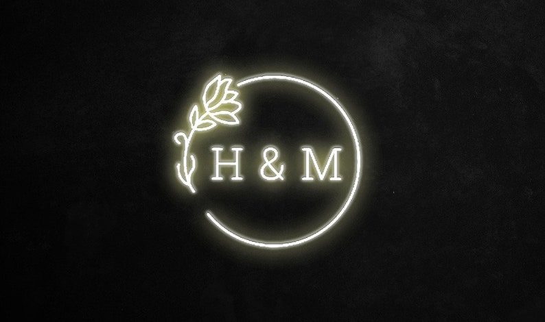 May include: A white neon sign with a floral design and the text "H & M" in a circle.