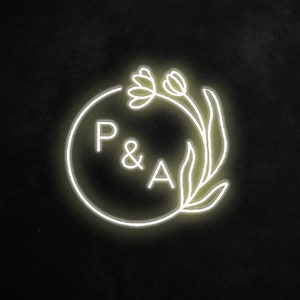 May include: A white neon sign with a circle and the letters "P & A" inside. The circle is surrounded by a stylized floral design.